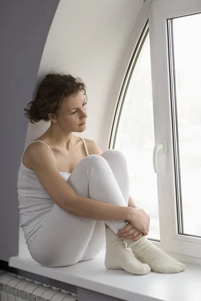 Mujer se sienta en el alféizar de la ventana —  Fotos de Stock