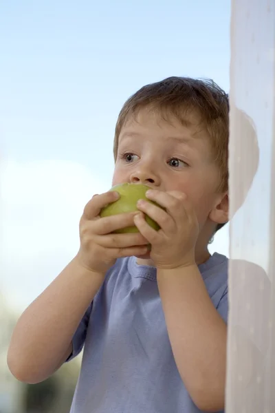 Młody chłopak gryzący w jabłko — Zdjęcie stockowe