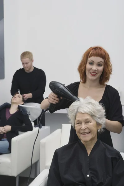 发型师吹发帖老年妇女的头发 — 图库照片