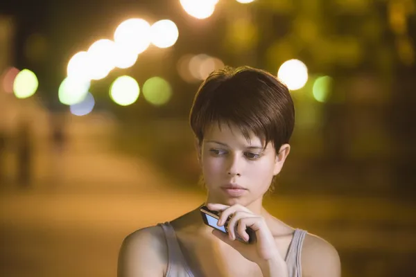 Adolescente chica se para pensando con el teléfono móvil en la calle —  Fotos de Stock