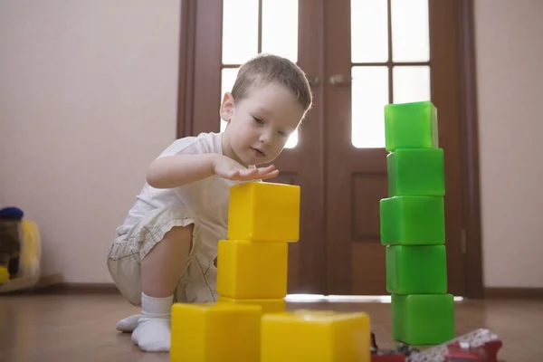 Young boy plays with green and yellow building bricks — Stock Photo, Image