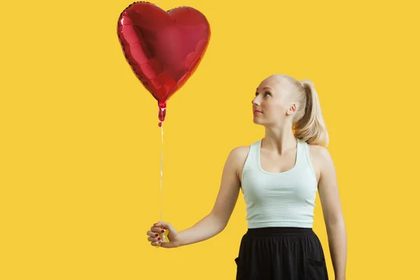 Vrouw kijken naar hartvormige ballon — Stockfoto