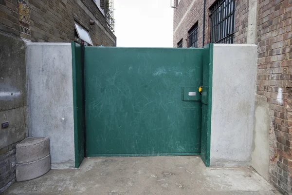 Portão verde ligado a edifícios — Fotografia de Stock