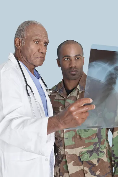 Doutor com soldado a olhar para o relatório de raio-x — Fotografia de Stock