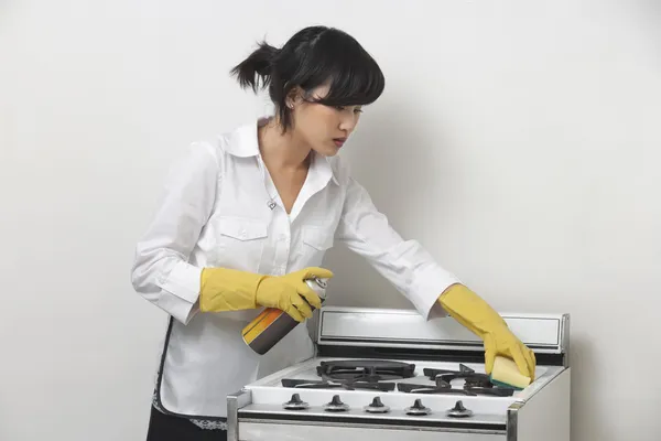 Maidservant cleaning stove — Stock Photo, Image