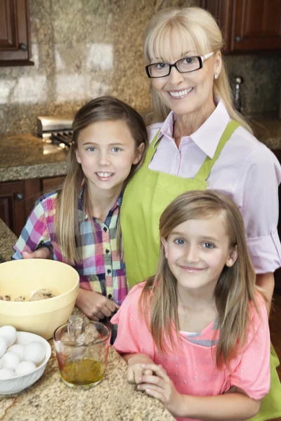 Mujer mayor con nietas en la cocina —  Fotos de Stock