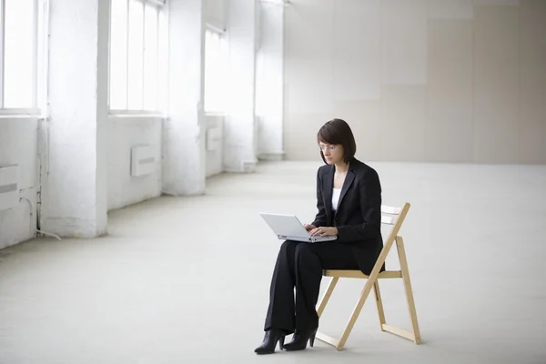 Business woman works on laptop in empty warehouse Stock Image