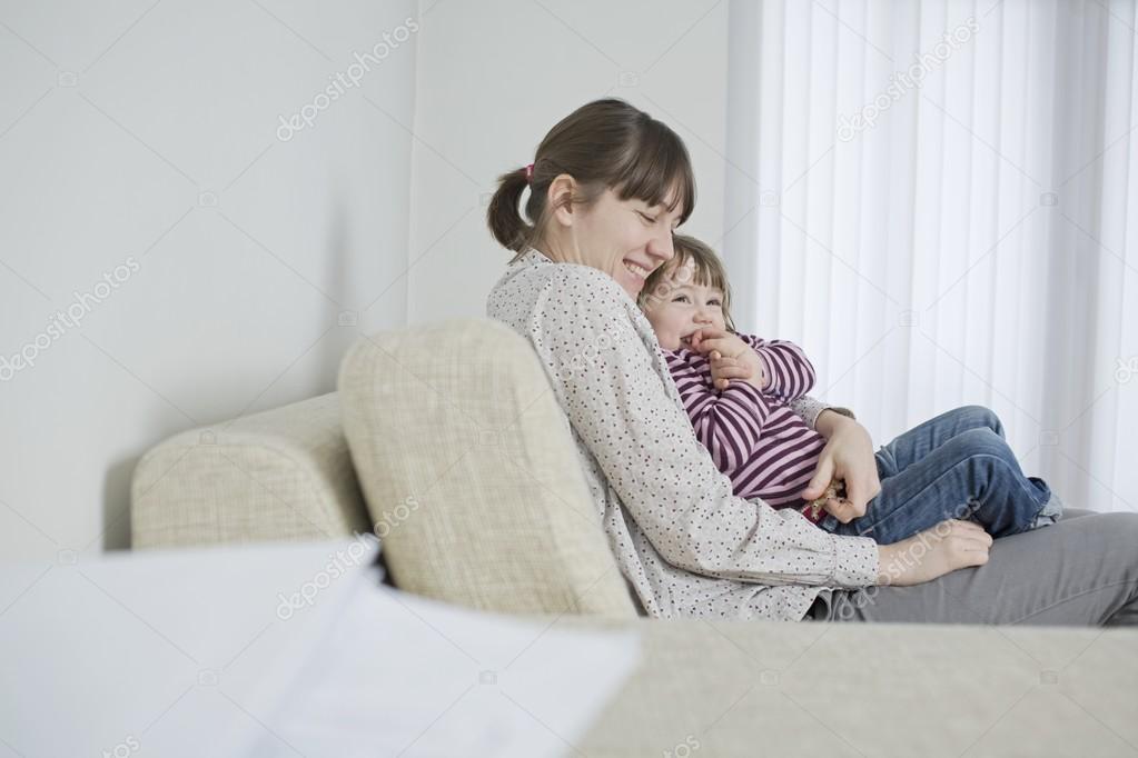 Mother and daughter cuddling on sofa