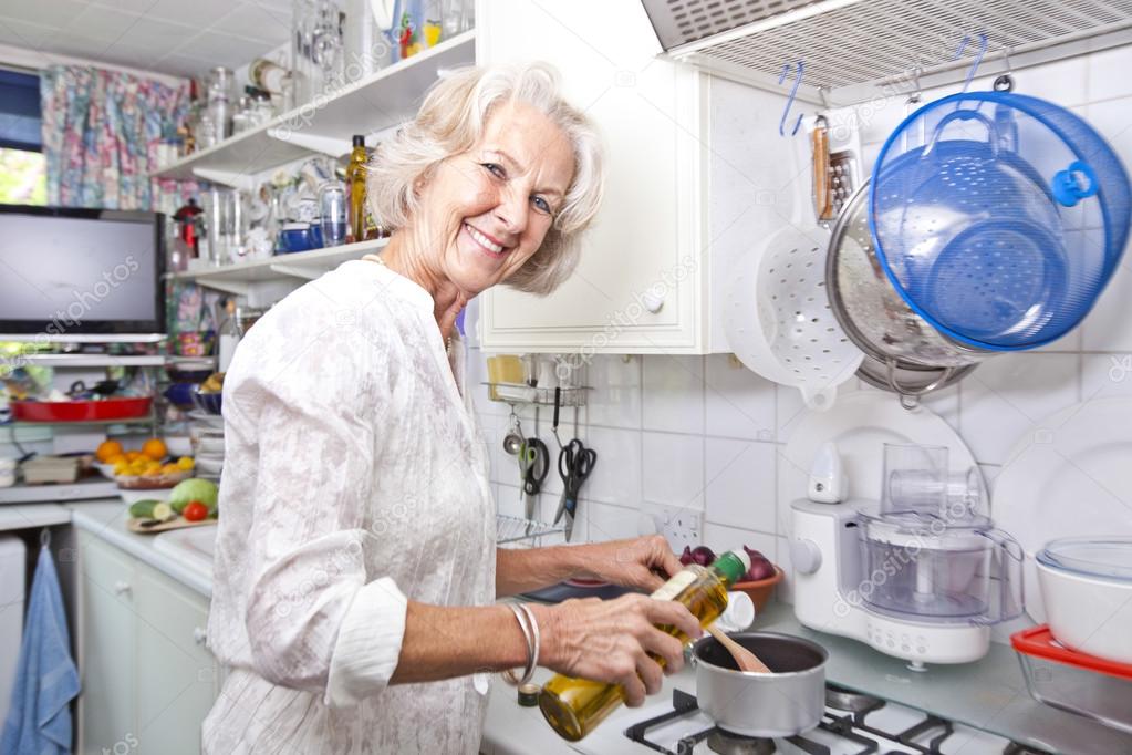 Senior woman pouring olive oil to saucepan