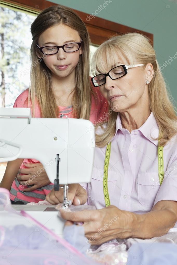 Granddaughter looking at grandmother sewing cloth