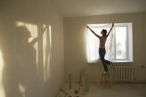Γυναίκα τοποθέτηση κουρτίνες σε νέο διαμέρισμα — Φωτογραφία Αρχείου