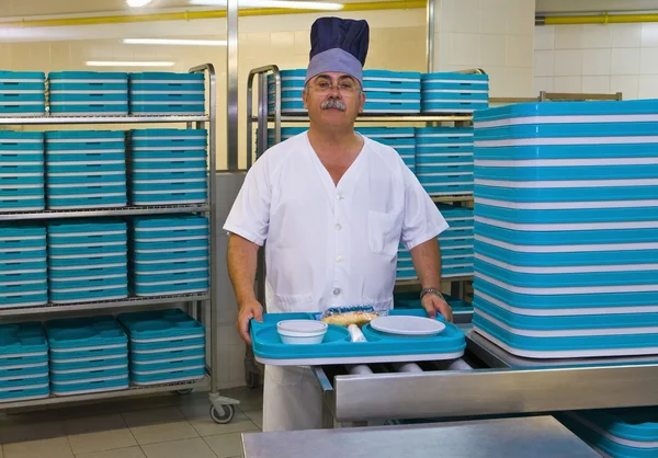 Chef fica na cozinha do hospital com bandejas de plástico — Fotografia de Stock