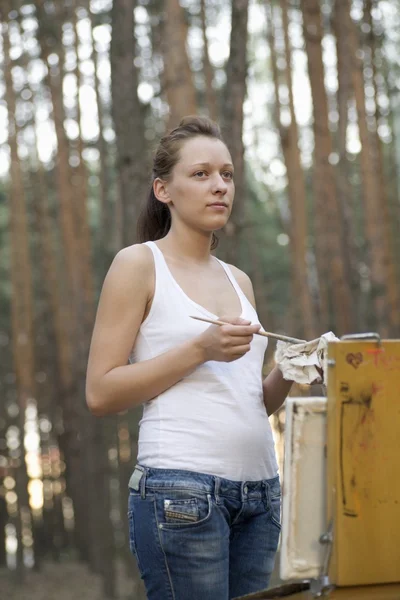 Artists stands painting on canvas in forest clearing — Stock Photo, Image