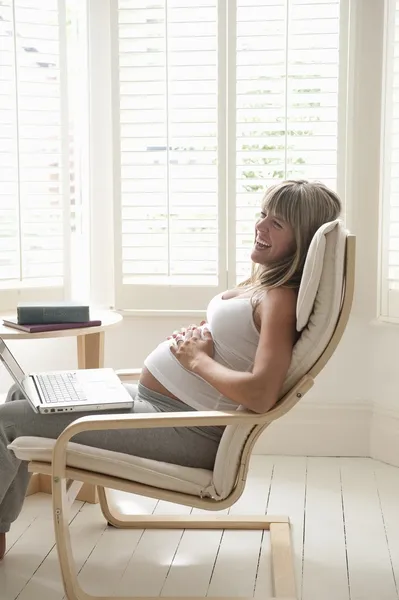 怀孕的女人坐在椅子上摸肚子 — 图库照片