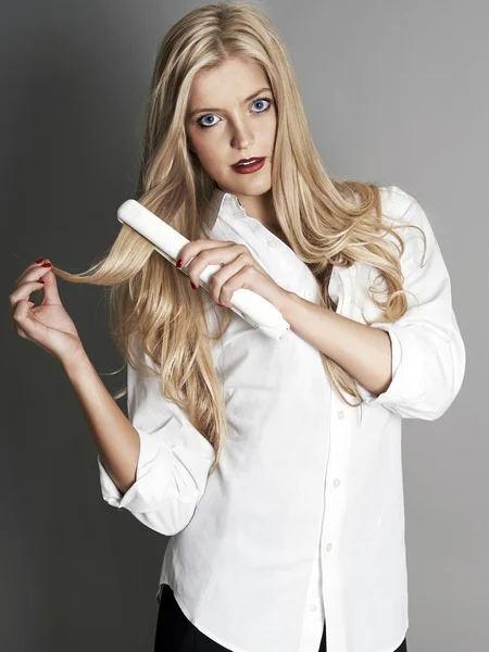 Blondýnka s žehlička na vlasy — Stock fotografie