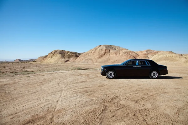 Luxury car parked on unpaved road near mountains — Stock Photo, Image