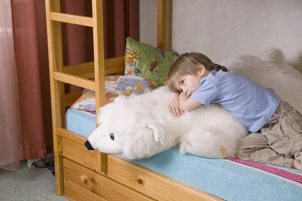 Niño de 5 años se encuentra en la litera con el oso polar juguete suave —  Fotos de Stock