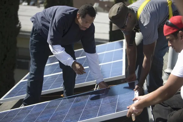 Homens levantando um grande painel solar — Fotografia de Stock