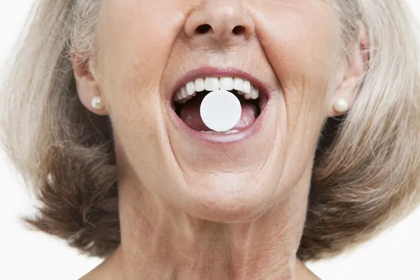 Woman with a pill between her teeth — Stock Photo, Image