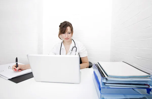 Arzt mit Laptop schreibt Notizen — Stockfoto