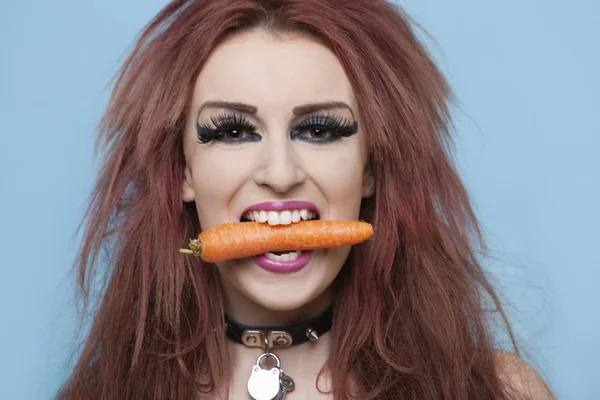 Funky woman holding carrot in mouth — Stock Photo, Image
