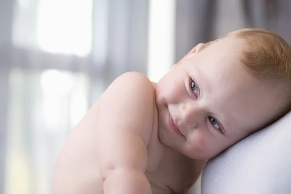 Criança bonito senta-se olhando para os lados e sorrindo — Fotografia de Stock
