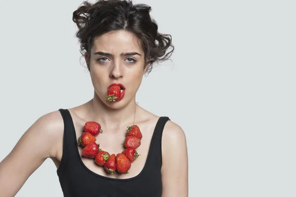 Woman wearing strawberry necklace while biting one piece — Stock Photo, Image