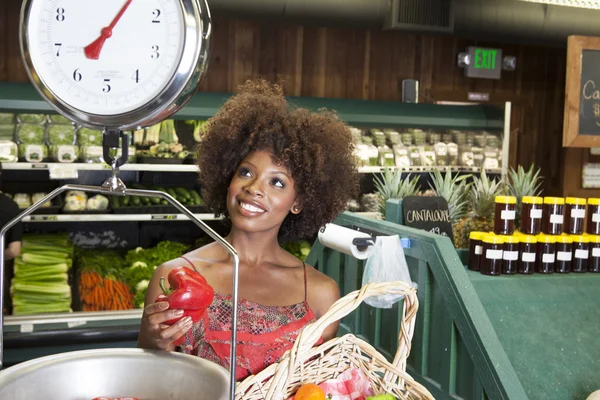 Woman weighing peppers on scale — Stock Photo, Image