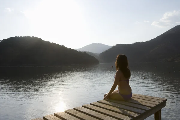 Woman on lakeside jetty — Stock Photo, Image