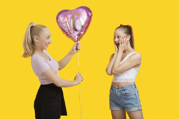 Mujer dando globo de cumpleaños a mujer asombrada — Foto de Stock