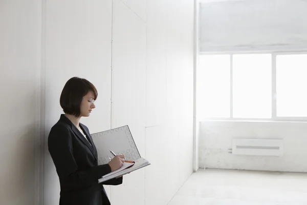 Business woman stands with file in empty warehouse — Stock Photo, Image