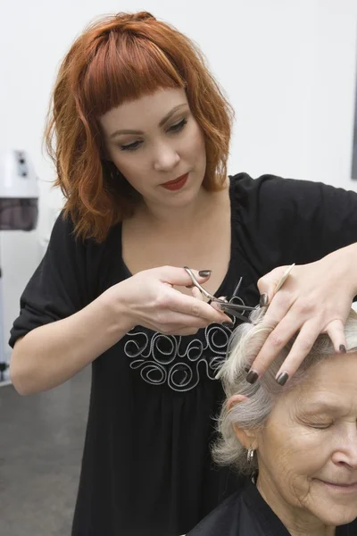 Stylista ścina włosy starsza kobieta — Zdjęcie stockowe