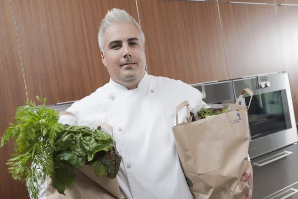 Midden-adult chef-kok met twee zakken van verse boodschappen — Stockfoto