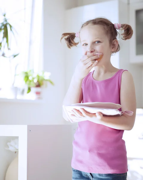 Girl eating cake in kitchen — Stock Photo, Image