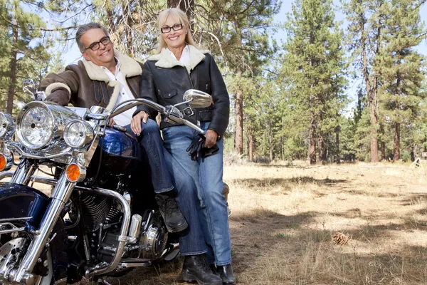 Senior couple lean on motorcycle in forest — Stock Photo, Image