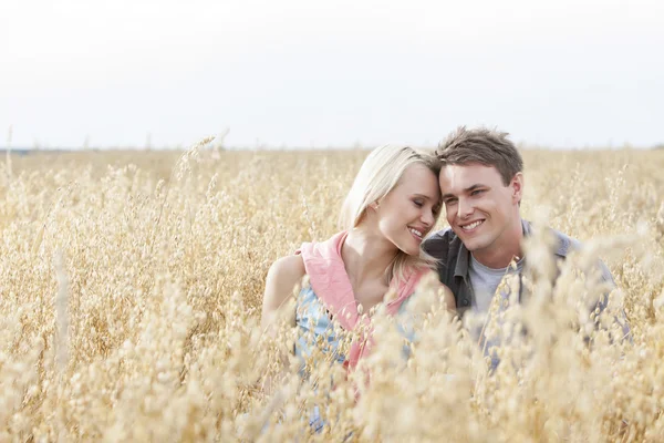 Couple sitting amidst field — Stock Photo, Image