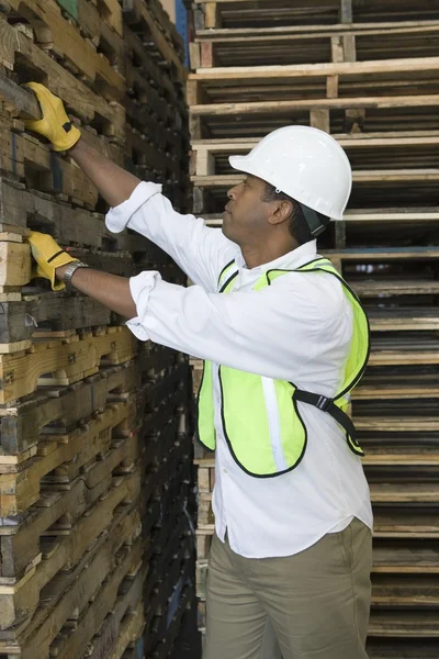 Homem que inspeciona paletes de madeira — Fotografia de Stock