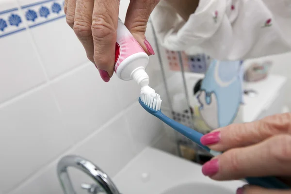 Mujer poniendo pasta dental en cepillo — Foto de Stock