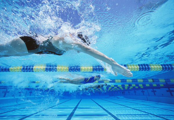 female swimmers racing in swimming pool 