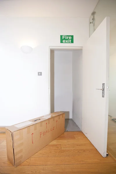 Cardboard box marked "fragile" by fire exit — Stock Photo, Image
