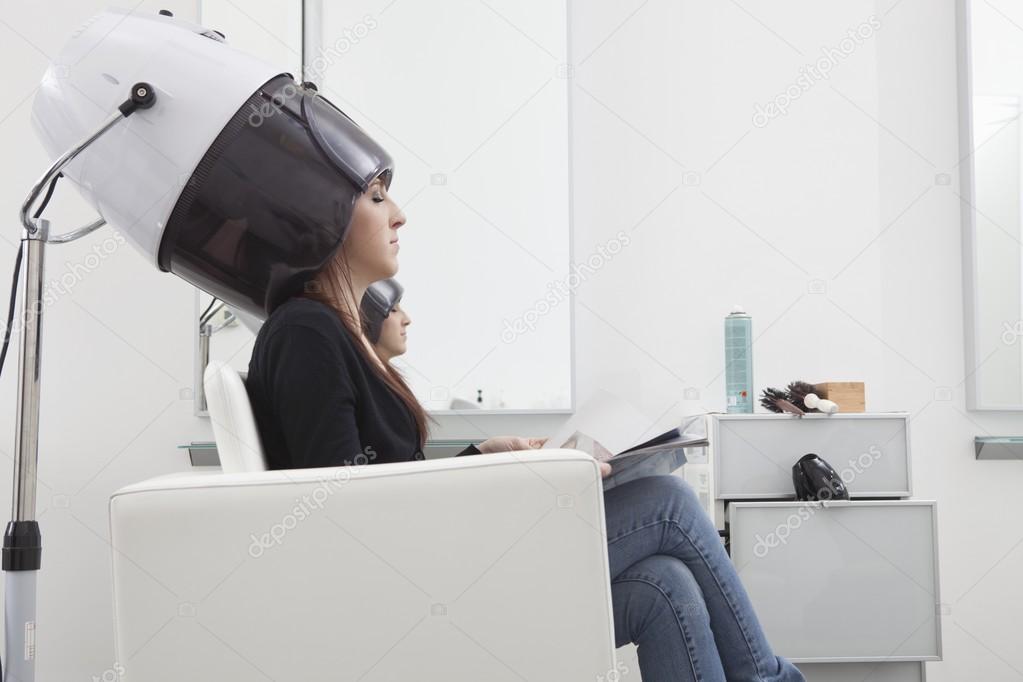 Female client sits under drying hood in hair salon — Stock Photo