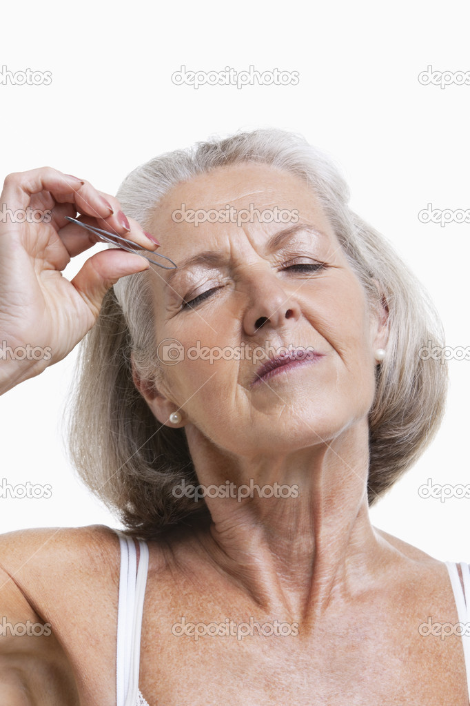 Senior woman tweezing eyebrows