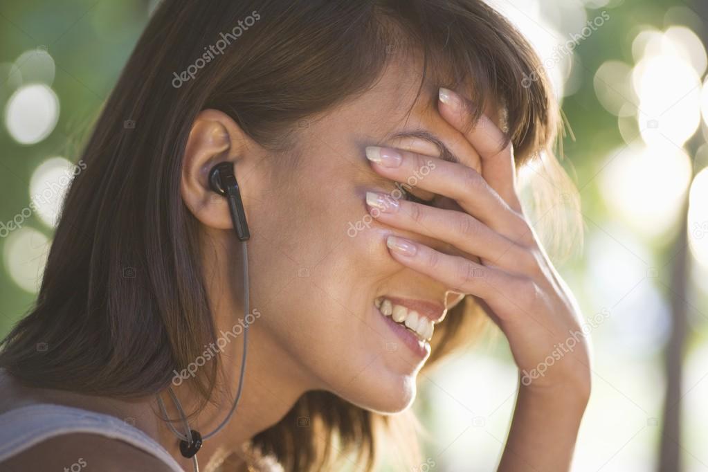 Woman covers her face laughing with headphones