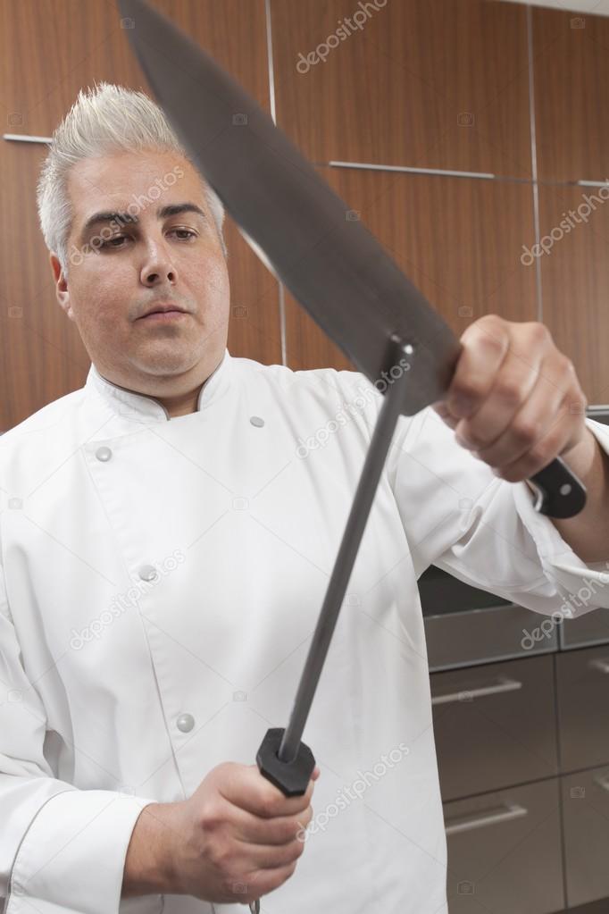 Mid- adult chef sharpens knife