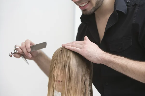 Man cutting and combing womans hair — Stock Photo, Image