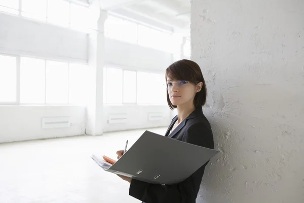 Business woman with file in empty warehouse — Stock Photo, Image