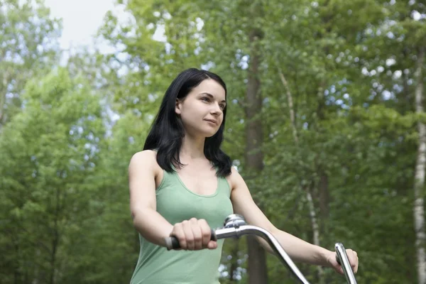 Jeune femme se tient avec vélo dans les bois — Photo