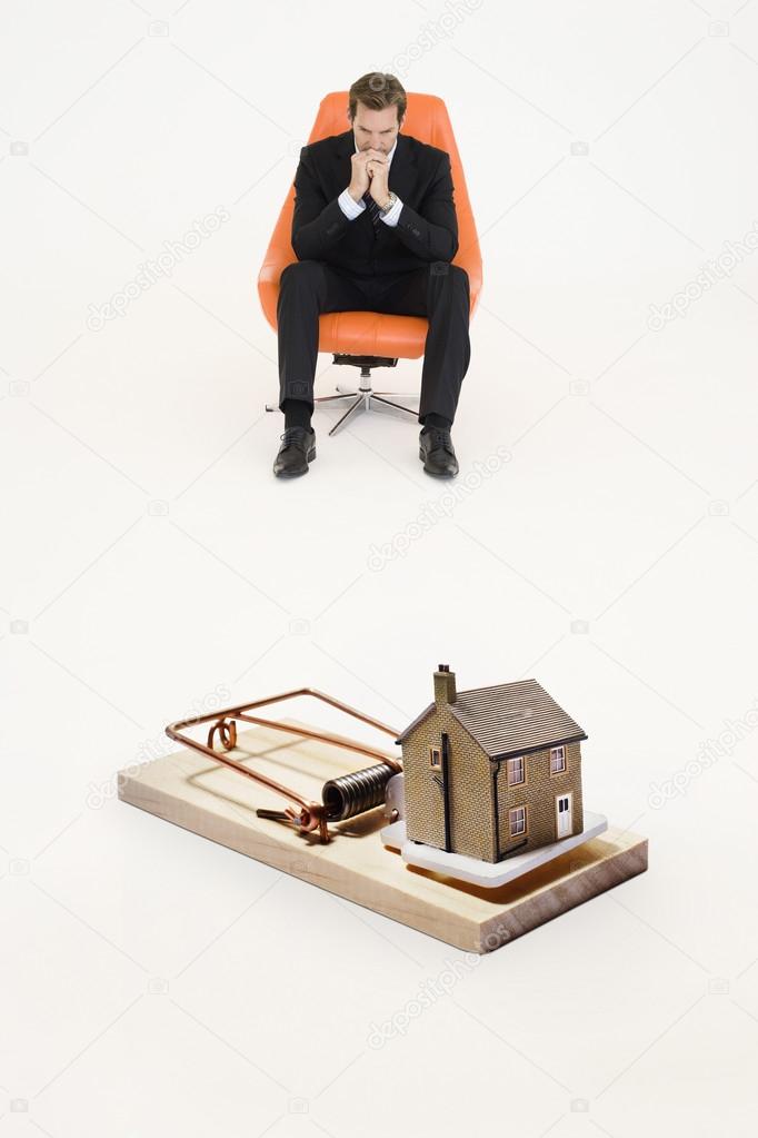 Model home on mouse trap with worried businessman
