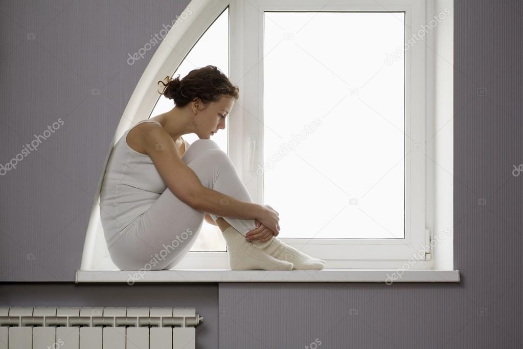 woman sits on windowsill