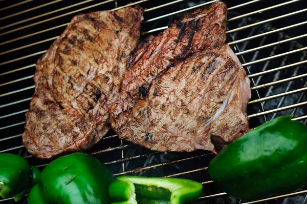 Steaks with green pepper on a grill — Stock Photo, Image